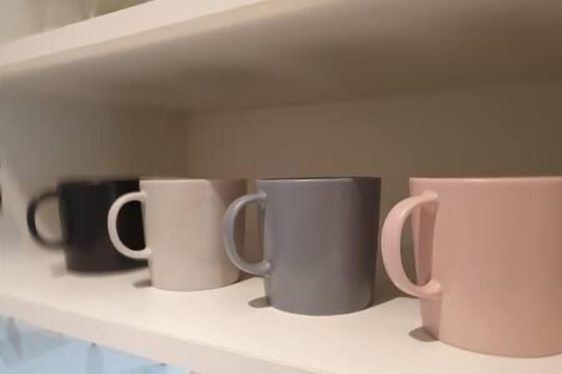 A shelf with four mugs in different colors.