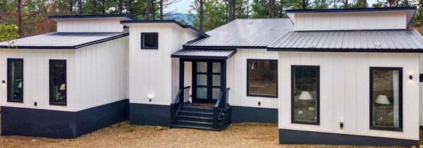 A row of white cabins with black trim, each featuring a small porch and a window. - Bent Not Broken Bow Resort Cabin in Broken Bow (Broken Bow,)