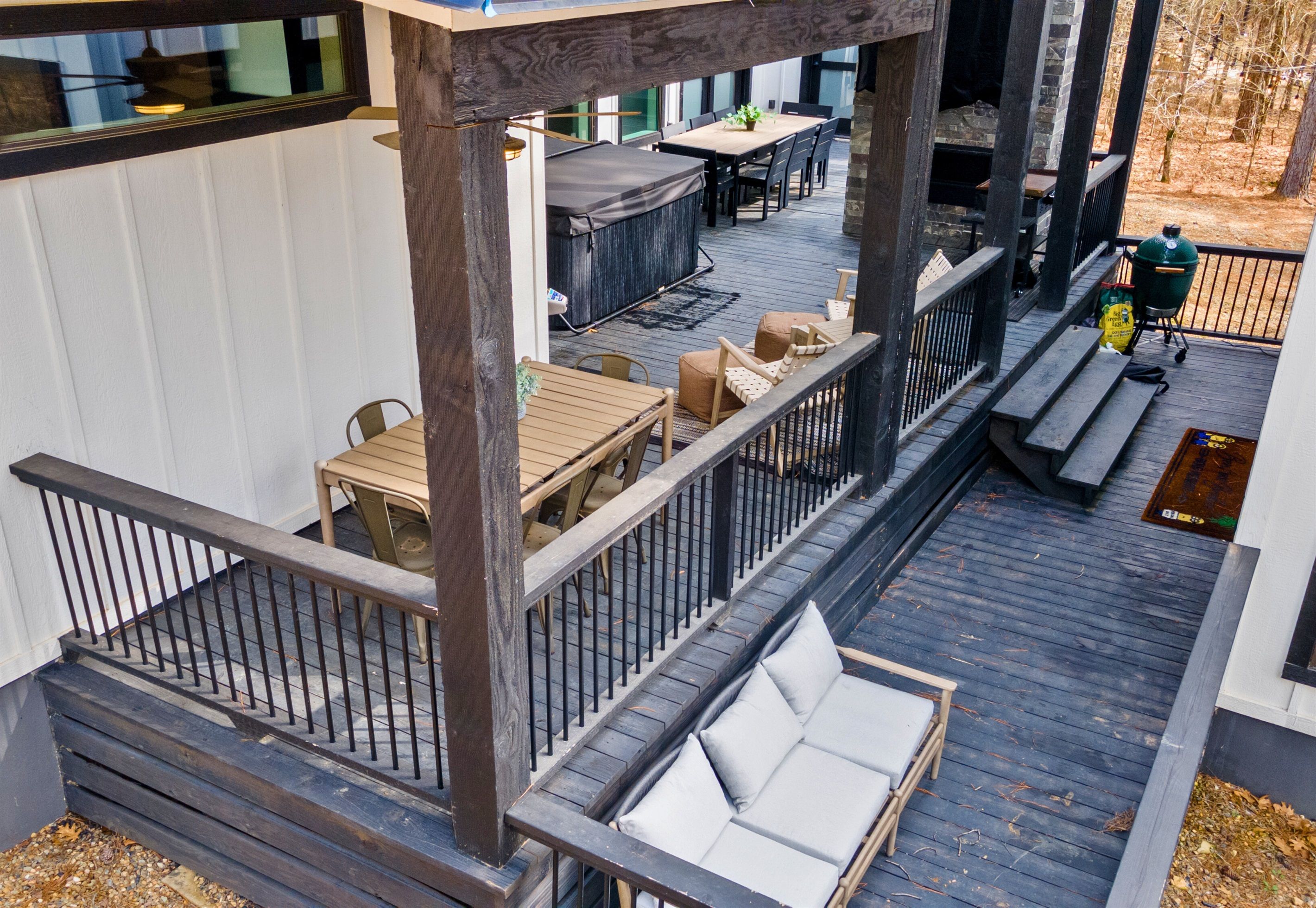 Eine überdachte Terrasse im Freien mit Tisch, Stühlen, einer Bank und einem Grill.