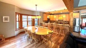 Een ruime keuken met houten kasten, een centraal eiland en een eetgedeelte met een ronde tafel en stoelen.