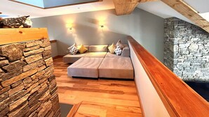 Een gezellig loft slaapkamer met een stenen muur, houten balken in het plafond en een stenen open haard.