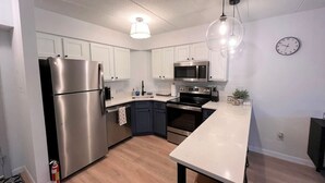 Una cocina moderna con electrodomésticos de acero inoxidable, armarios blancos y una isla central.