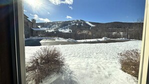 Paisaje nevado con una montaña al fondo y un edificio con porche en primer plano.