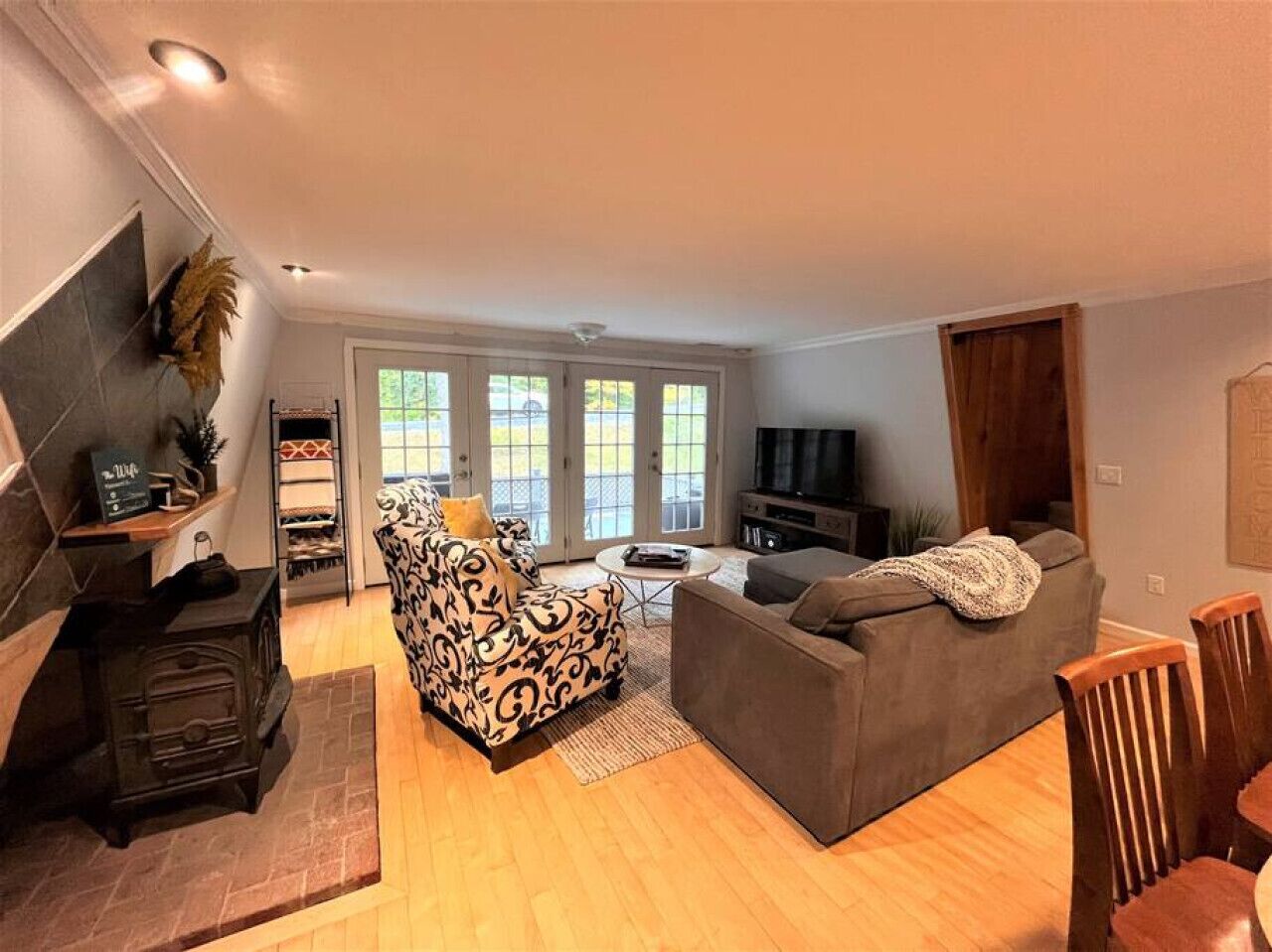 Ein Wohnzimmer mit Kamin, Sofa, Sessel und Fernseher.