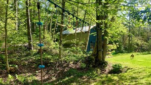 A forested area with a rope swing, a small building, and a dog in the distance. - New! Mt Snow Chalet w/land, privacy, relaxation (Dover)