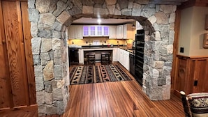 A kitchen with stone archways, wooden flooring, and white cabinets. - New! Min from Mt & Town. Hot tub, Stream + privacy (Wilmington)