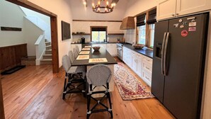 A modern kitchen with a central island, wooden flooring, and a chandelier. - New! Min from Mt & Town. Hot tub, Stream + privacy (Wilmington)