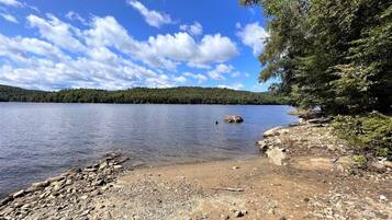 A rocky shoreline with a clear view of a lake and distant hills.