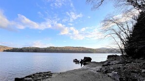 Eine felsige Küste mit einem ruhigen See und weit entfernten Hügeln.