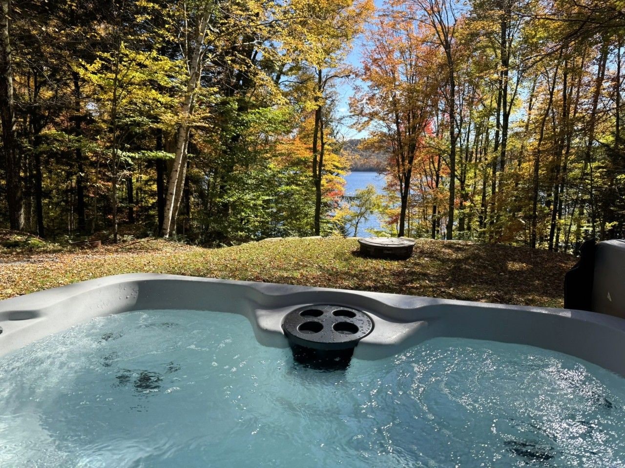A hot tub surrounded by trees with a lake in the background.