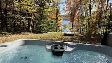 A hot tub surrounded by trees with a lake in the background.