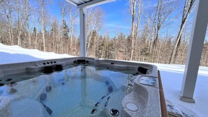 Ein Whirlpool mit freiem Blick auf eine verschneite Landschaft und kahle Bäume.