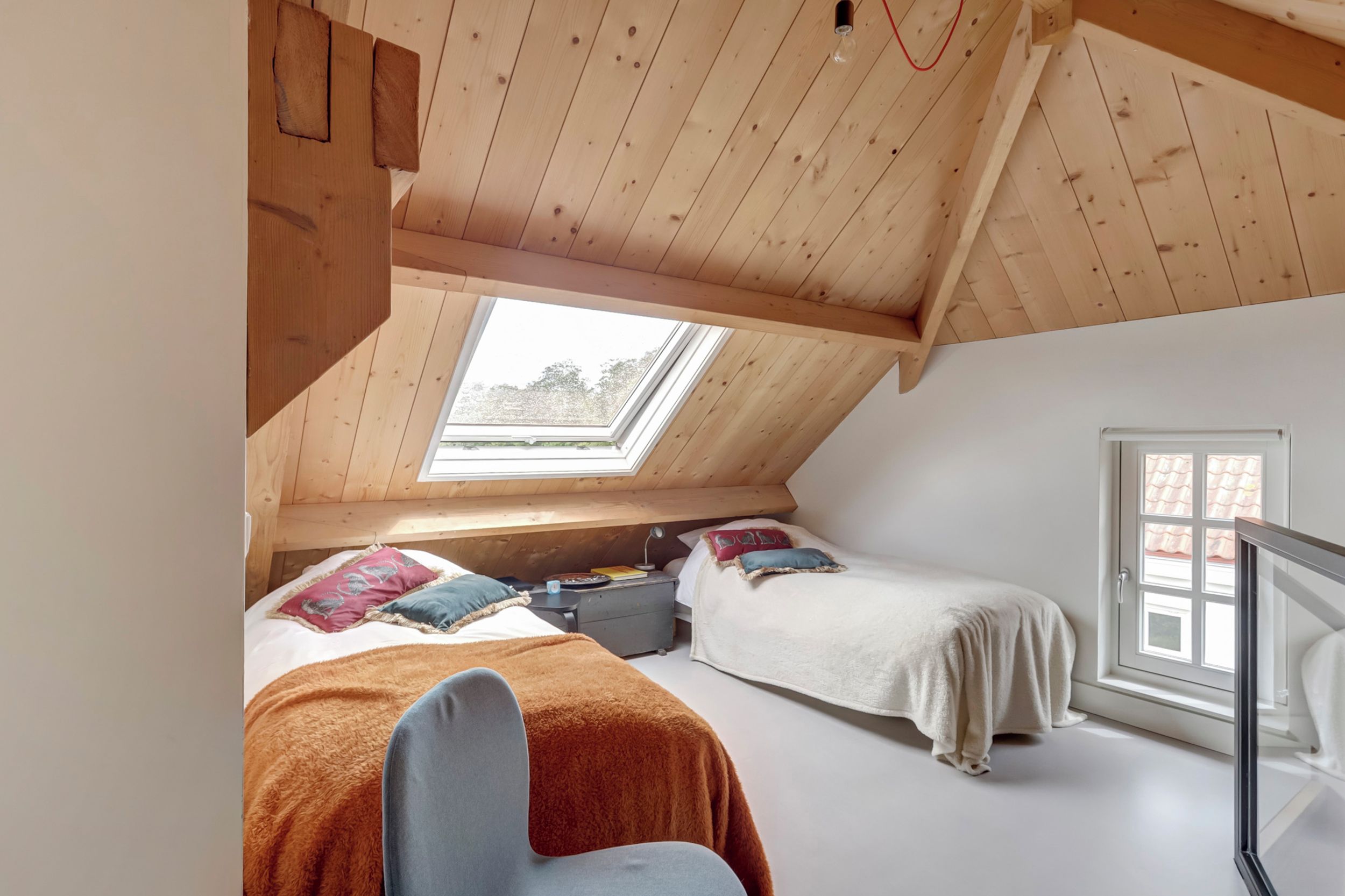 A bedroom with two beds, a skylight, and a window.
