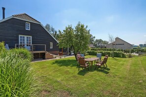 A house with a large yard, a hammock, and a table with chairs.
