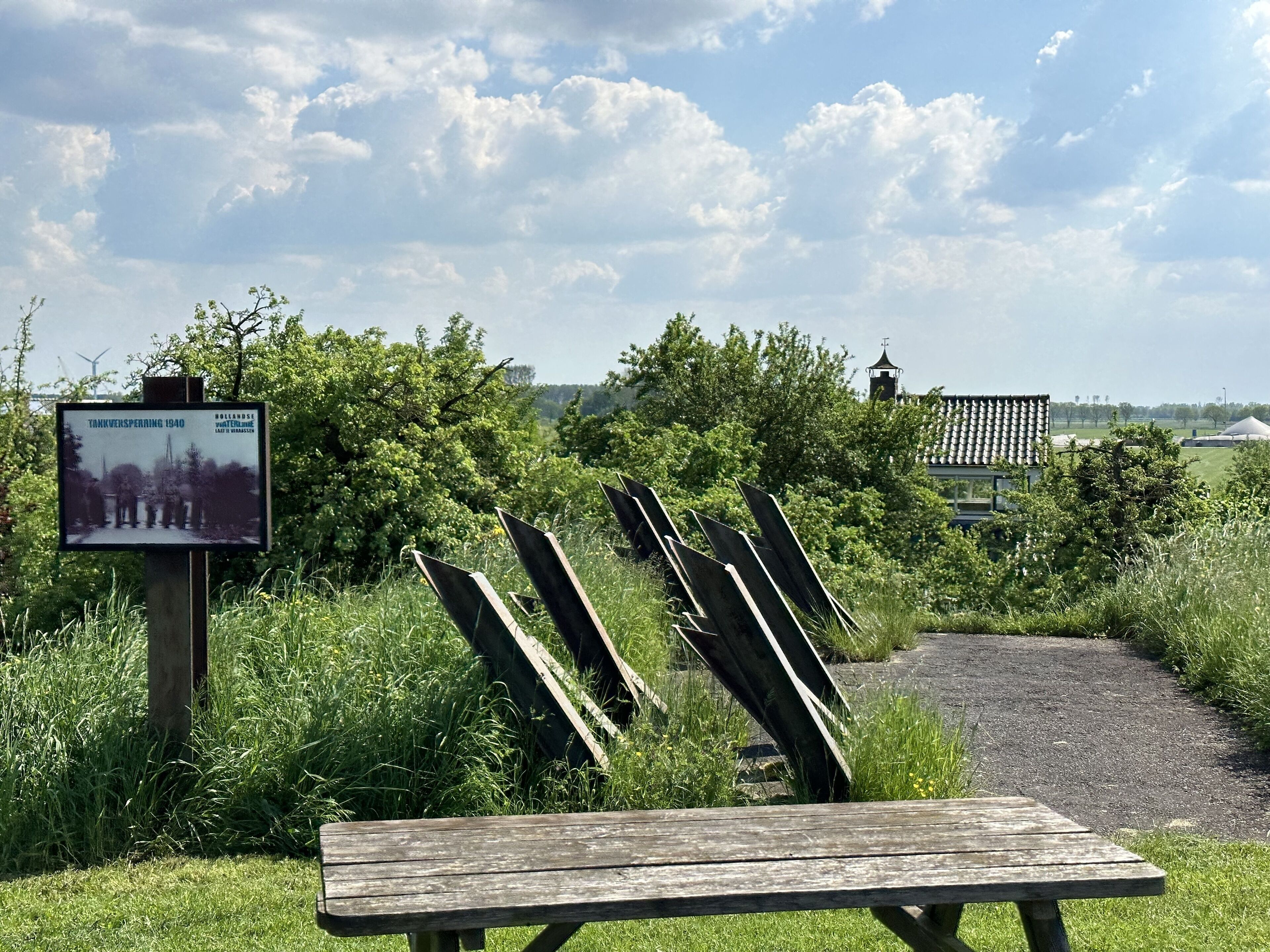 A picnic table in a park with a sign in the background.