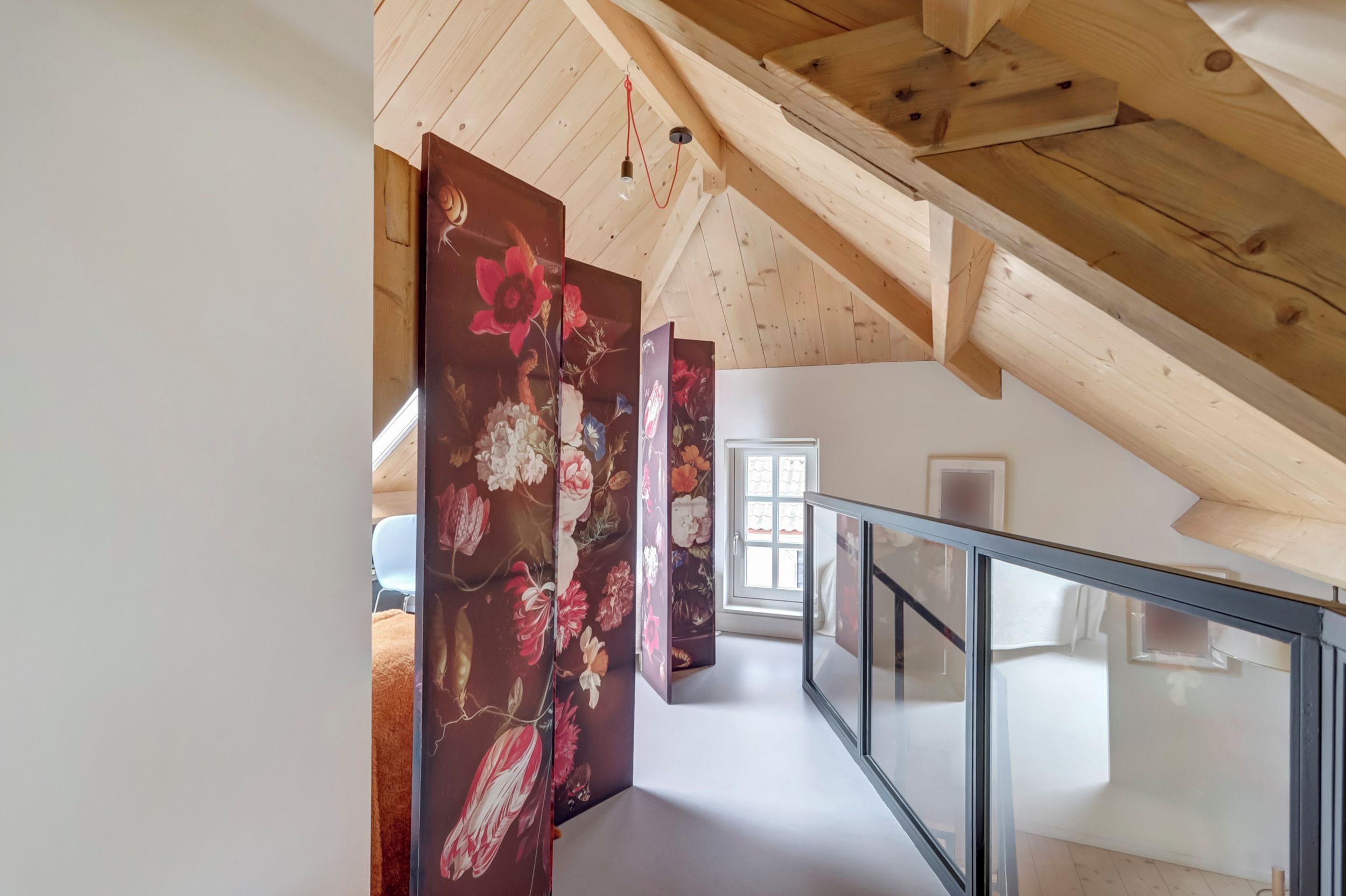 A staircase with a glass railing leading to a room with a wooden ceiling and a door with a window.
