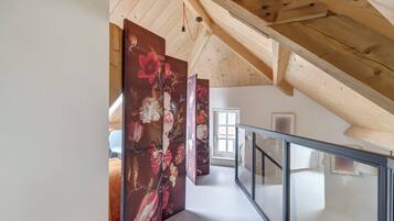 A staircase with a glass railing leading to a room with a wooden ceiling and a door with a window.