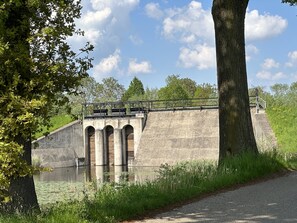 A concrete dam with a pedestrian walkway and a bridge. - Ruime, Ouderwets Gezellige Voormalige Schuur Midden in de Natuur (Culemborg)