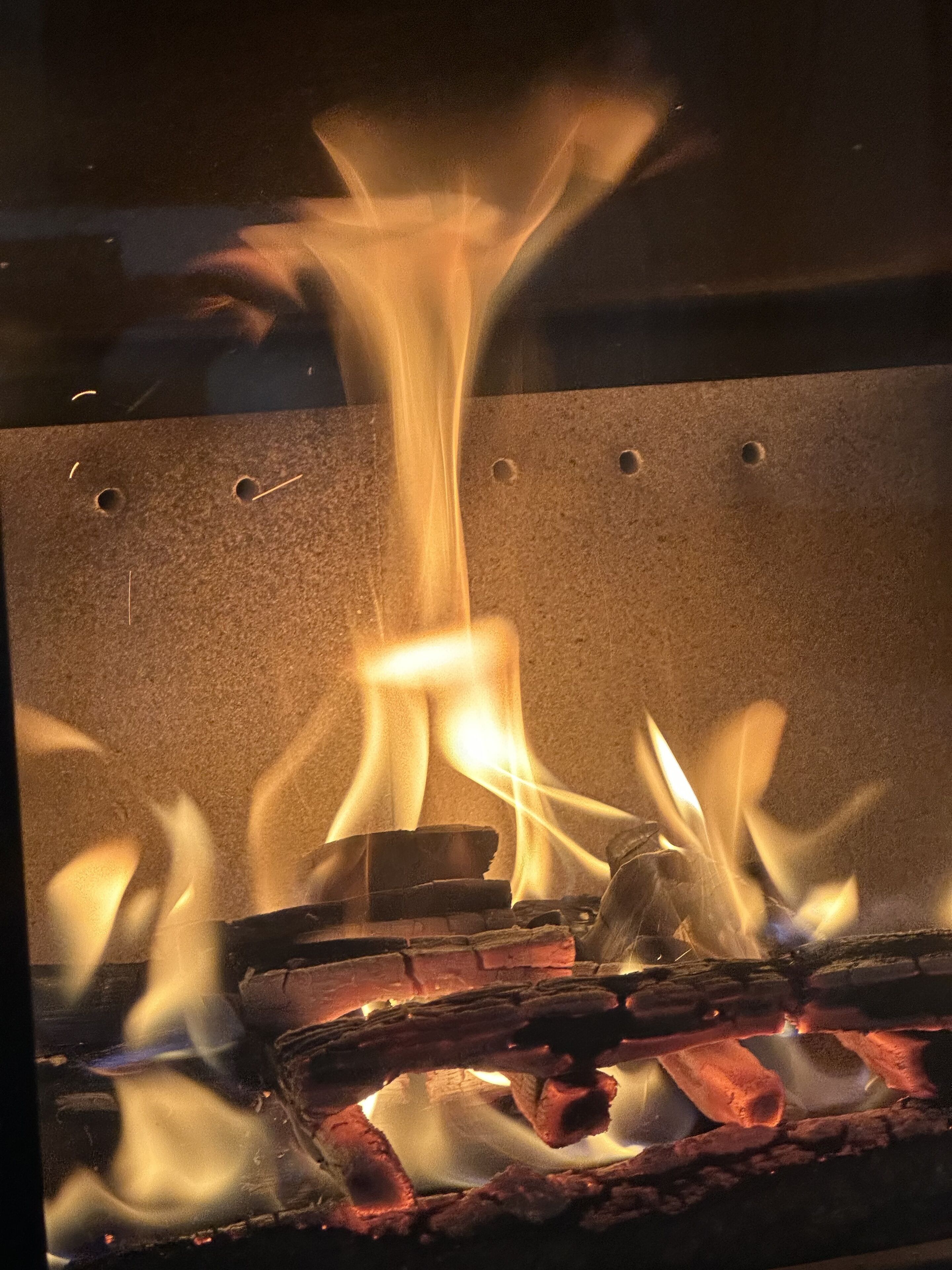 Ein Nahblick auf ein Feuer mit sichtbaren Flammen und Holzscheiten.