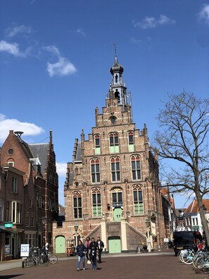 A historic building with a prominent tower, large windows, and a green door. - Ruime, Ouderwets Gezellige Voormalige Schuur Midden in de Natuur (Culemborg)