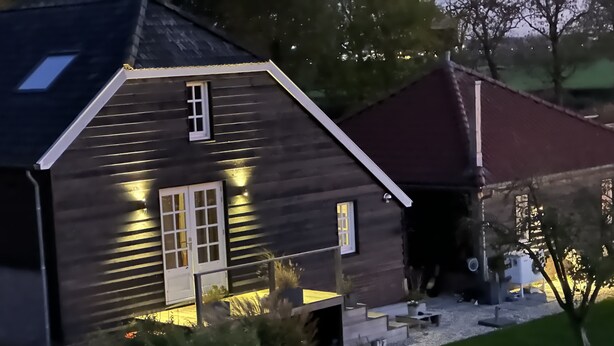 Una casa de fusta amb teulada inclinada, un porxo davanter i un garatge petit adossat.