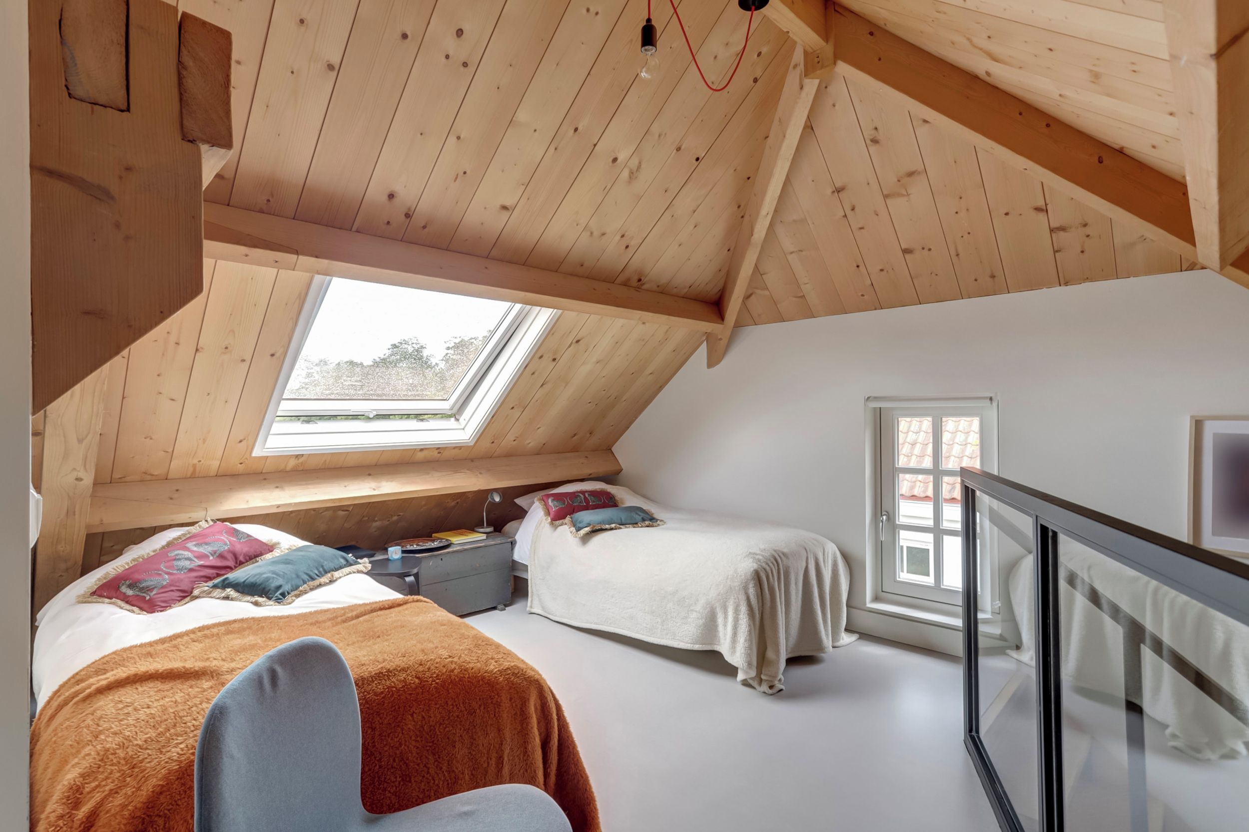 A bedroom with two beds, a skylight, and a window.