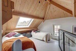 A bedroom with two beds, a skylight, and a window.