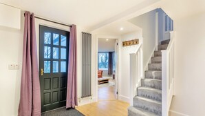 Interior moderno com uma escada, uma porta preta com janela e um corredor que leva a uma sala de estar.