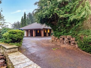 Un chalet rustique avec une allée en gravier, des murs en pierre et une végétation luxuriante.