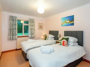 Une chambre d’hôtel avec deux lits, une fenêtre avec des rideaux, un tableau au mur et une lampe sur la table de chevet.