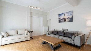 A modern living room with two sofas, a wooden coffee table, and a painting on the wall. - Corner penthouse in Acropolis (Athina)
