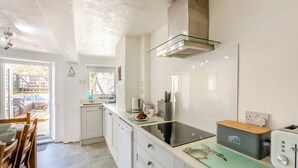 A modern kitchen with white cabinets, a glass backsplash, and a stainless steel range hood. - 3 bedroom accommodation in Silecroft, near Millom (Silecroft, near Millom)