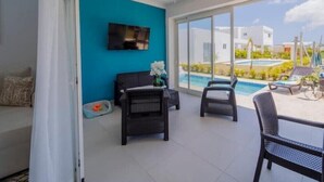 A spacious room with a large sliding glass door leading to a balcony with a pool view. - Villa Paradise Punta Cana (Punta Cana)