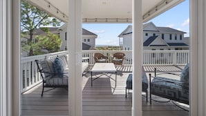 Une terrasse extérieure couverte, dotée d’une balustrade blanche, d’une table et de deux chaises en osier.
