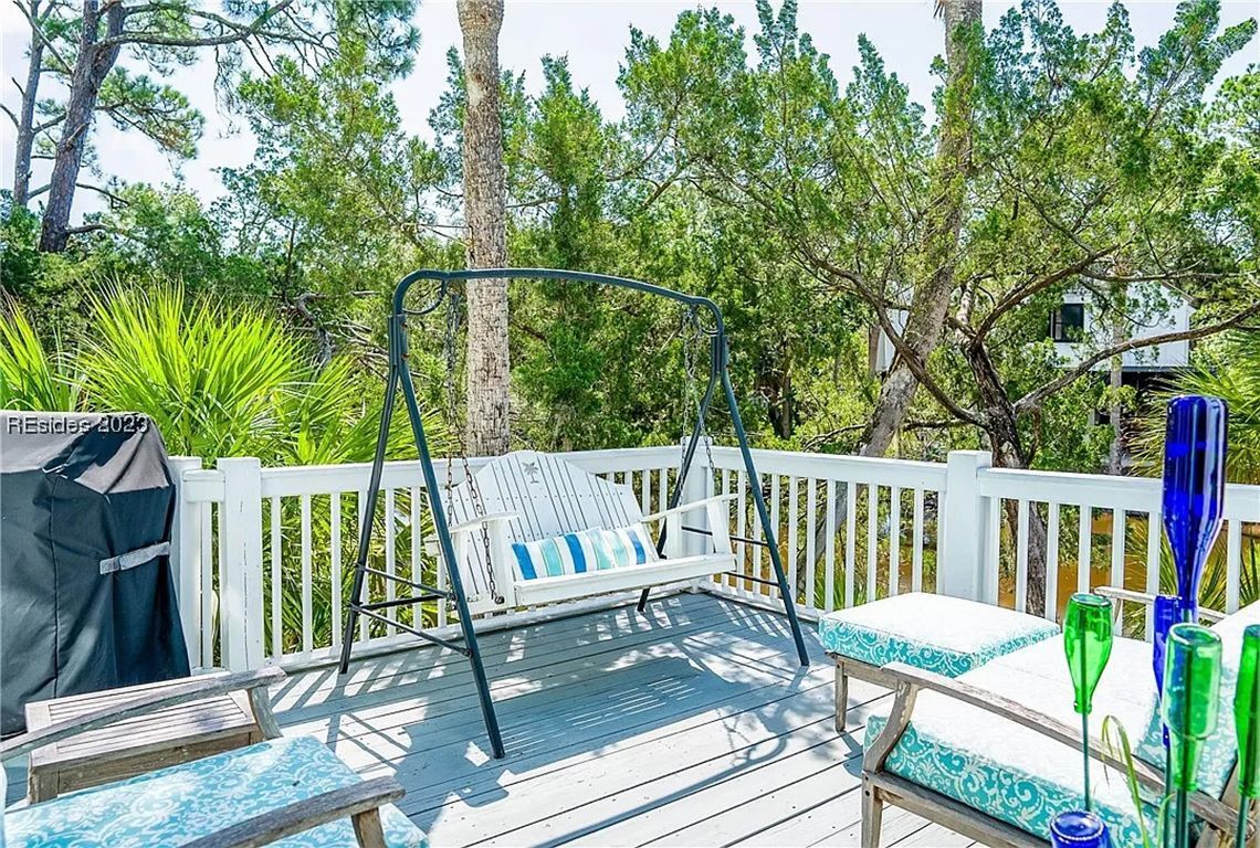 A wooden deck with a swing chair, a grill, and outdoor seating.