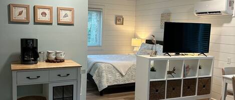 A bedroom with a bed, a TV, a desk, and a cabinet.