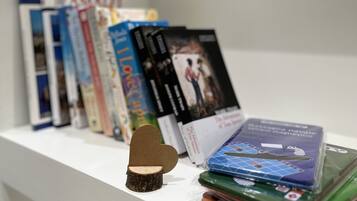 Una estantería con varios libros y un pequeño objeto con forma de corazón de madera.