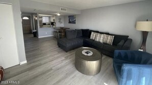A modern living room with a sectional sofa, a round coffee table, and a blue armchair. - North Mountain Townhouse (Phoenix)