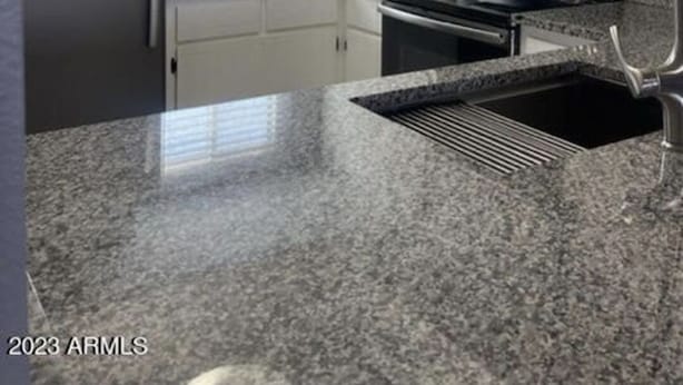 A modern kitchen with granite countertops, stainless steel appliances, and white cabinetry. - North Mountain Townhouse (Phoenix)