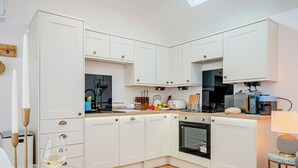 Une cuisine moderne avec des meubles blancs, un four encastré et un micro-ondes.