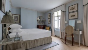 A bedroom with a large bed, a bedside table with a lamp, a chair, a dresser, and a mirror. - Burton Mews by onefinestay (London)