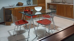 Een keuken met houten kasten, een glazen eettafel en rode stoelen.