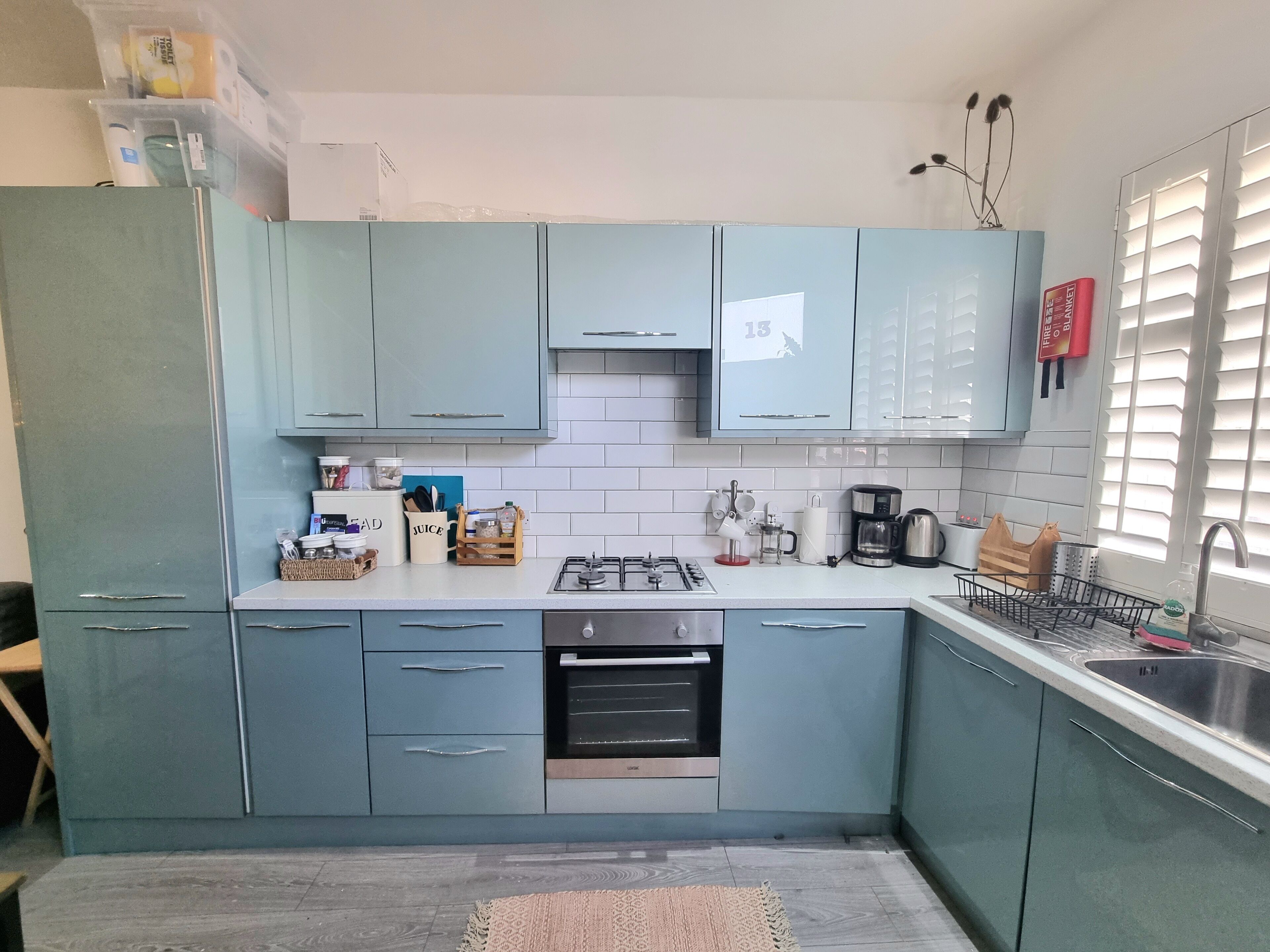 A kitchen with light blue cabinets, a gas stove, an oven, and a sink.