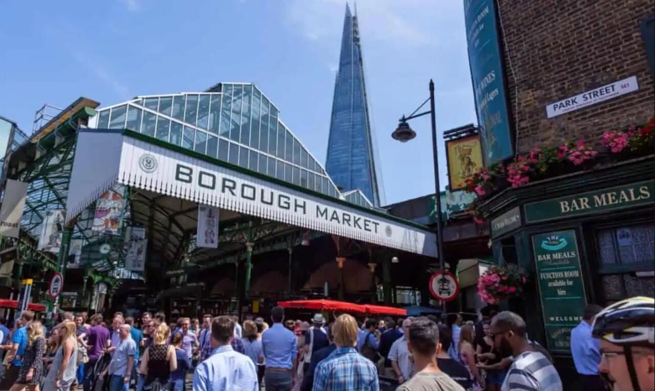 Mercado Borough com uma multidão de pessoas, um edifício moderno em vidro e uma estrutura de mercado tradicional.