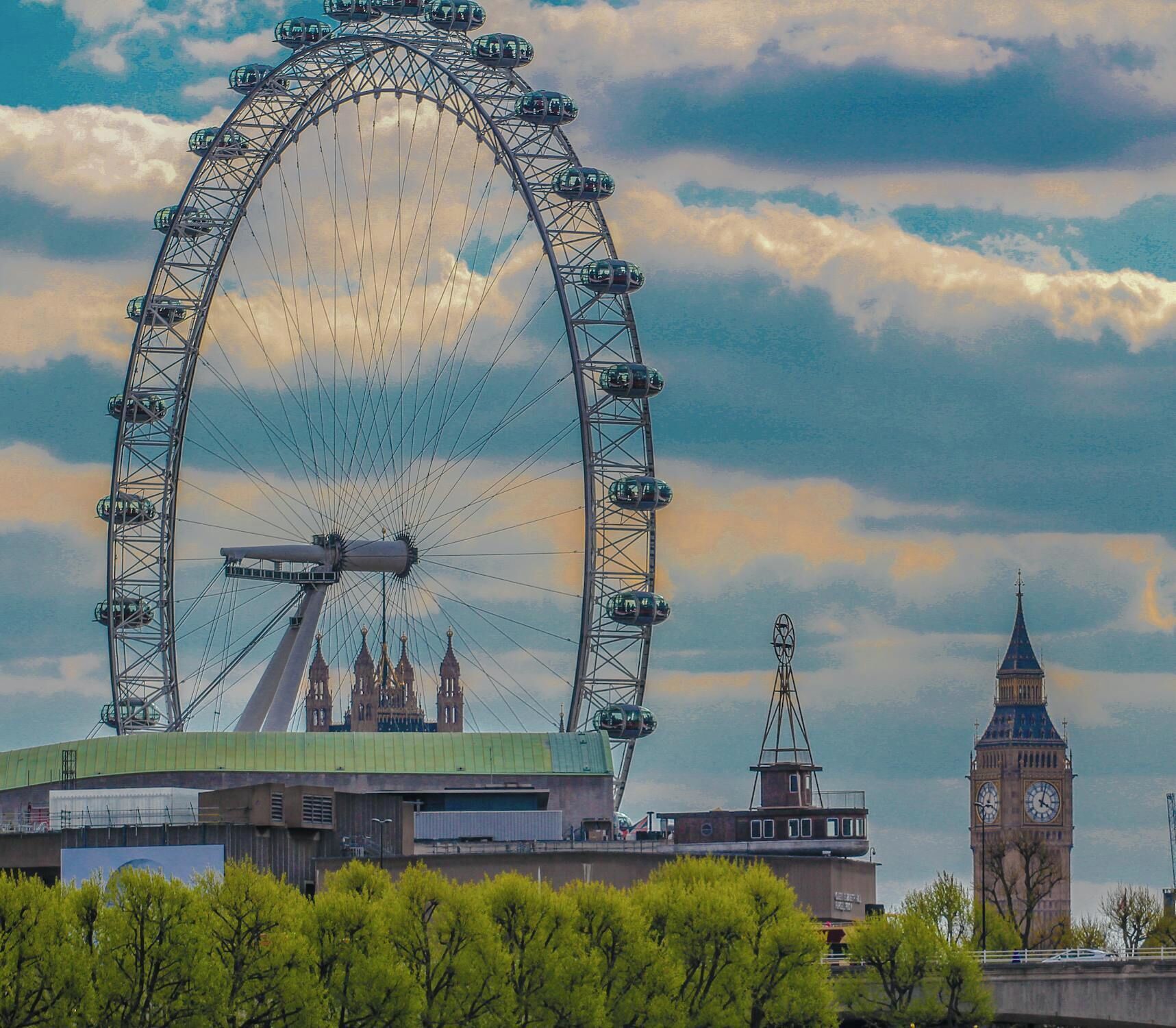 A large Ferris wheel with a green roof and a clock tower in the background.