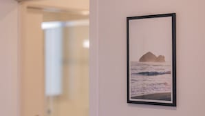 A framed photograph of a coastal scene with rocks and waves on a wall. - Casa ProMar - Sea View Serenity (Ponta Delgada)
