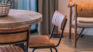 A round wooden table with two chairs, a small wire basket, and a floor lamp. - Casa ProMar - Sea View Serenity (Ponta Delgada)
