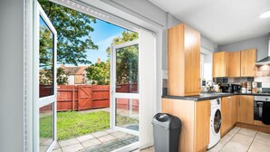 A modern kitchen with wooden cabinets, a washing machine, and a sliding glass door leading to a backyard. - Hotel Comforts & Home Conveniences -sleeps 8 (Birmingham)