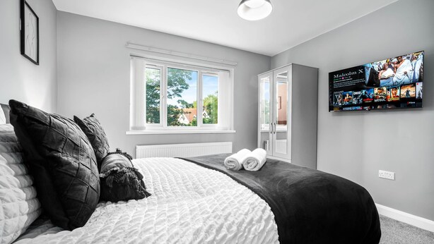 A bedroom with a bed, a window, a television, and a wardrobe. - Hotel Comforts & Home Conveniences -sleeps 8 (Birmingham)