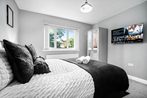 A bedroom with a bed, a window, a television, and a wardrobe. - Hotel Comforts & Home Conveniences -sleeps 8 (Birmingham)